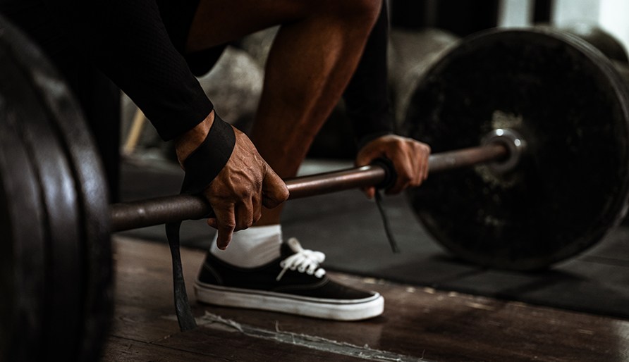 Henkil� k�ytt�� RAW SUPPS Leather Lifting Straps -vetoremmej� ja kiert�� ne tangon ymp�rille valmistautuen maastavetoon.